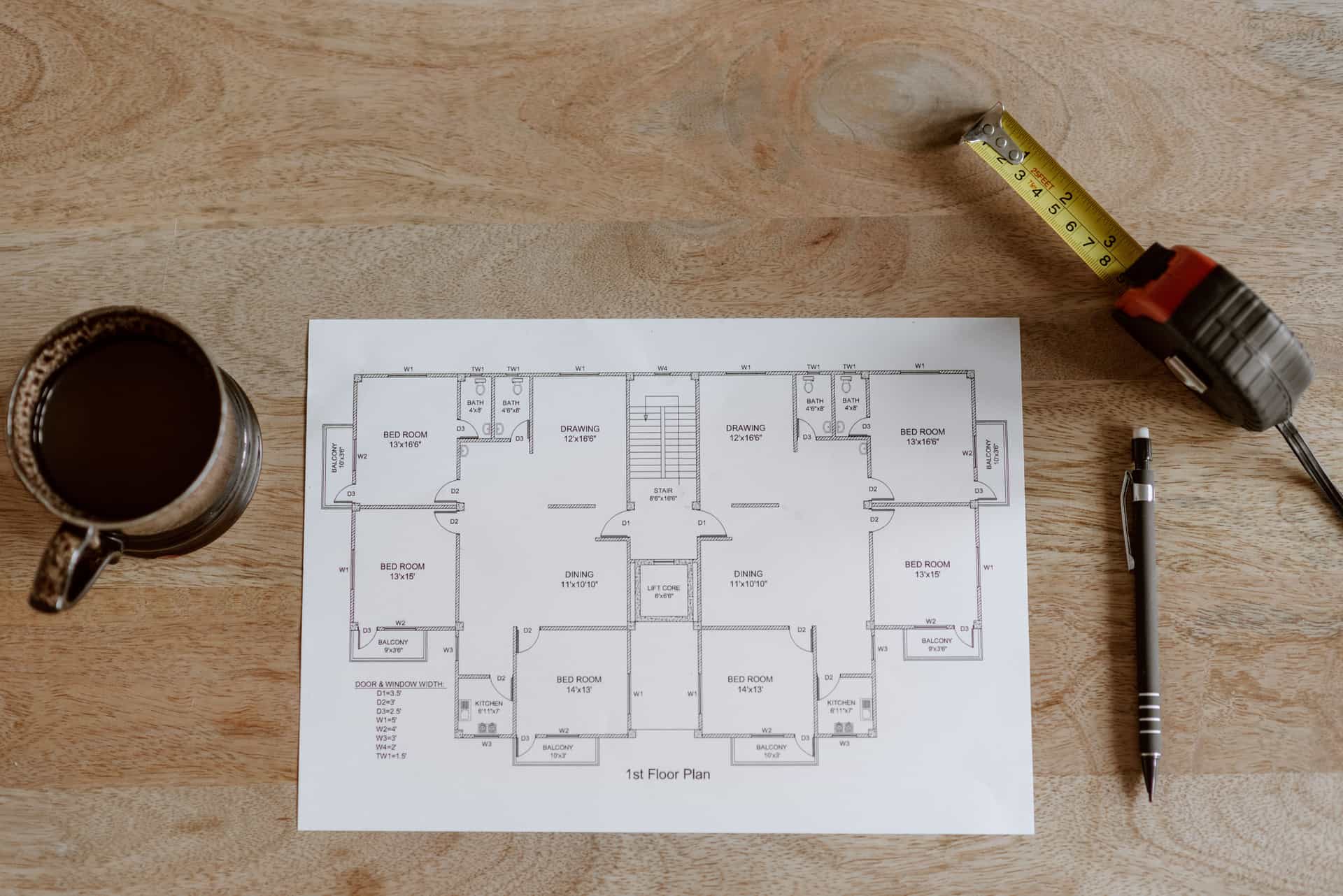 A tape measure and notepad on a wooden floor
