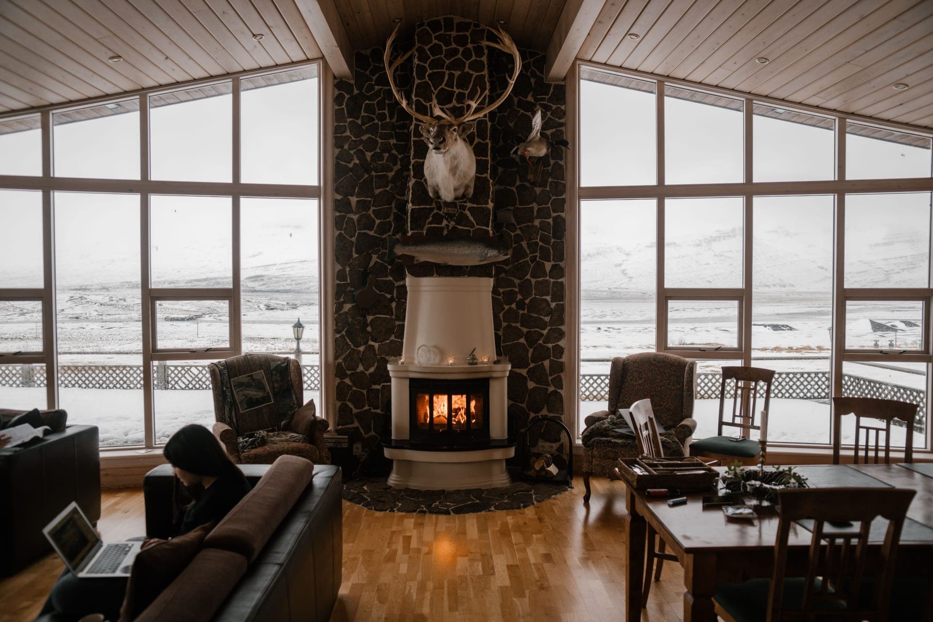 A warm living room with a fireplace and large windows