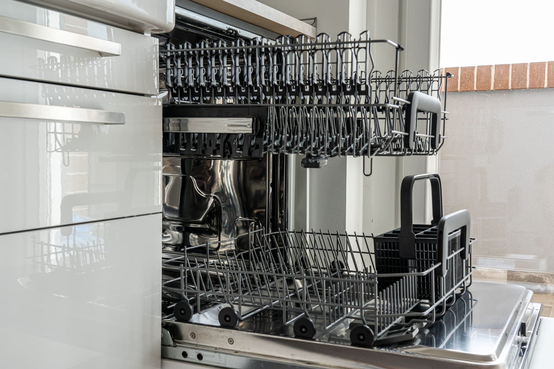 An open dishwasher rack in a sunlit kitchen