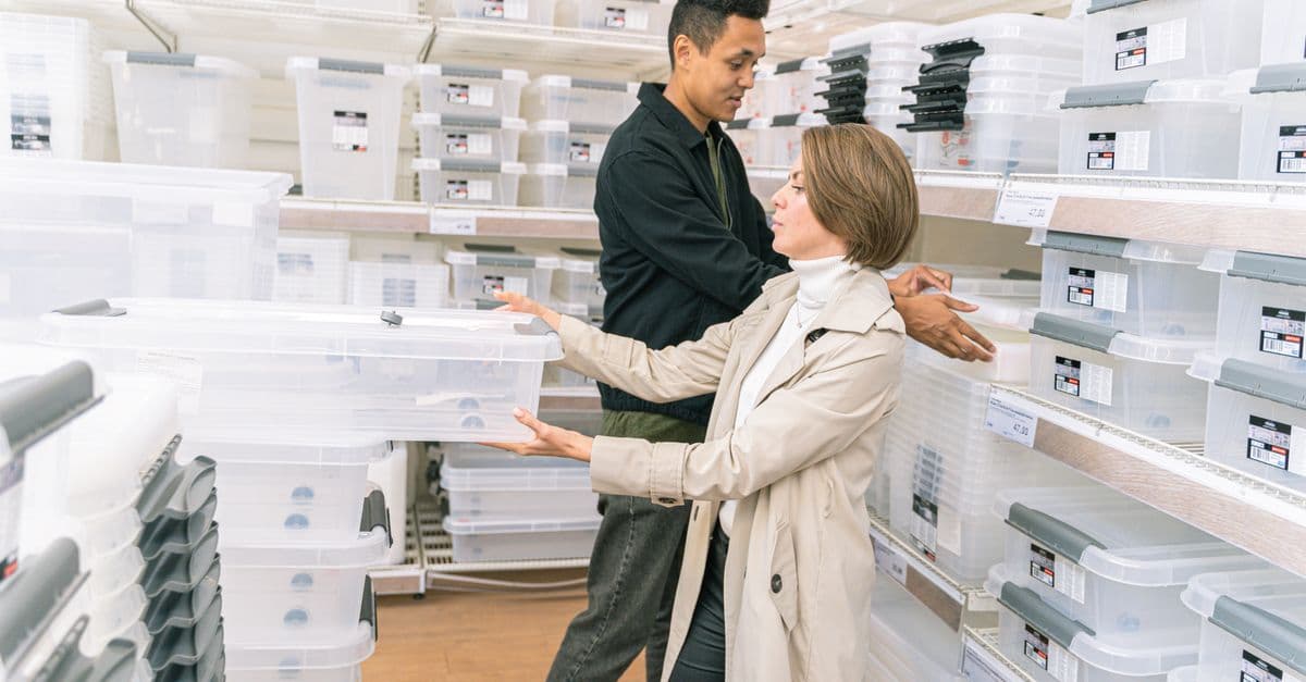 Two people comparing boxes on a shelf in a shop