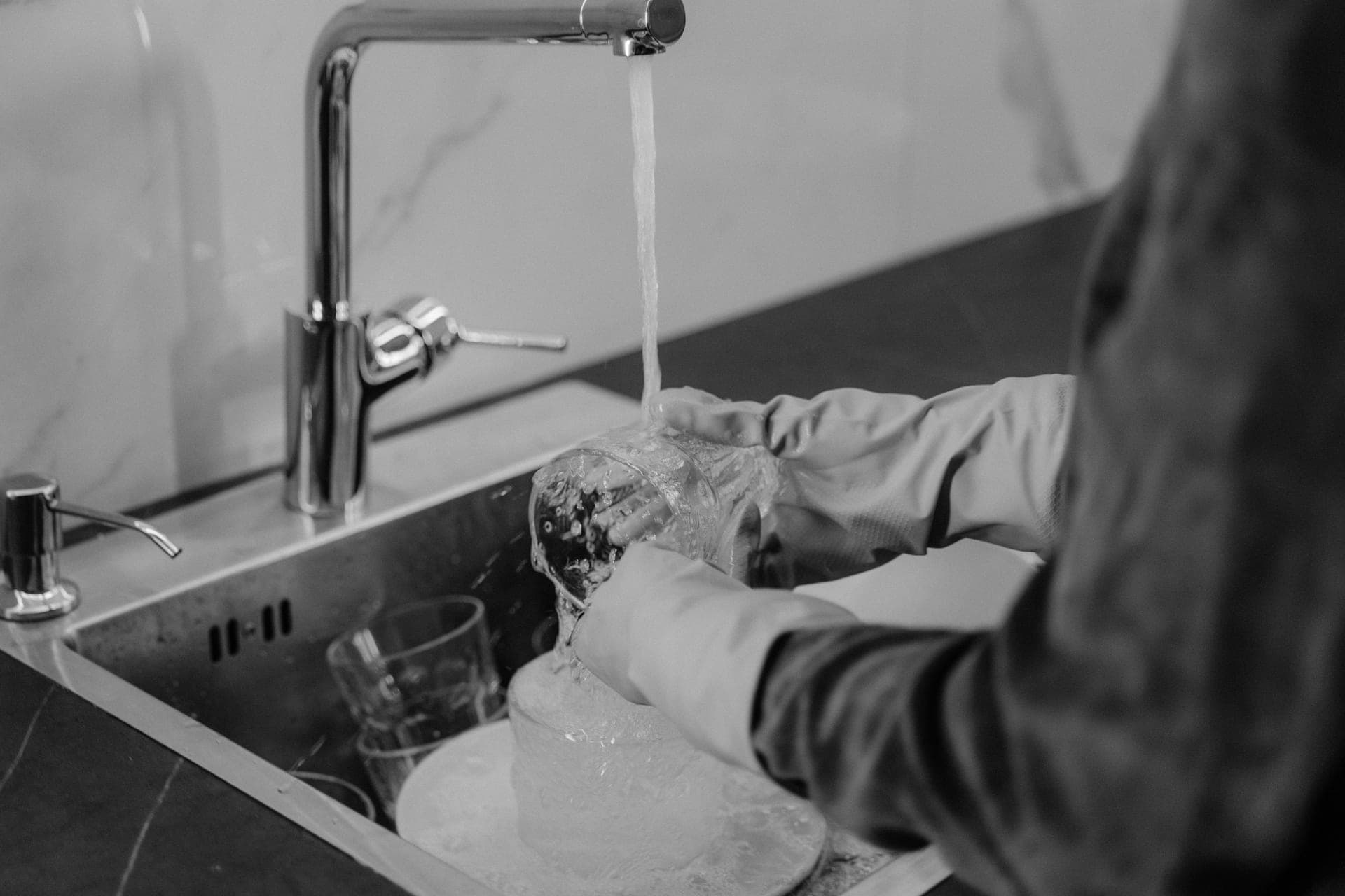 Appliance parts being rinsed at a kitchen sink