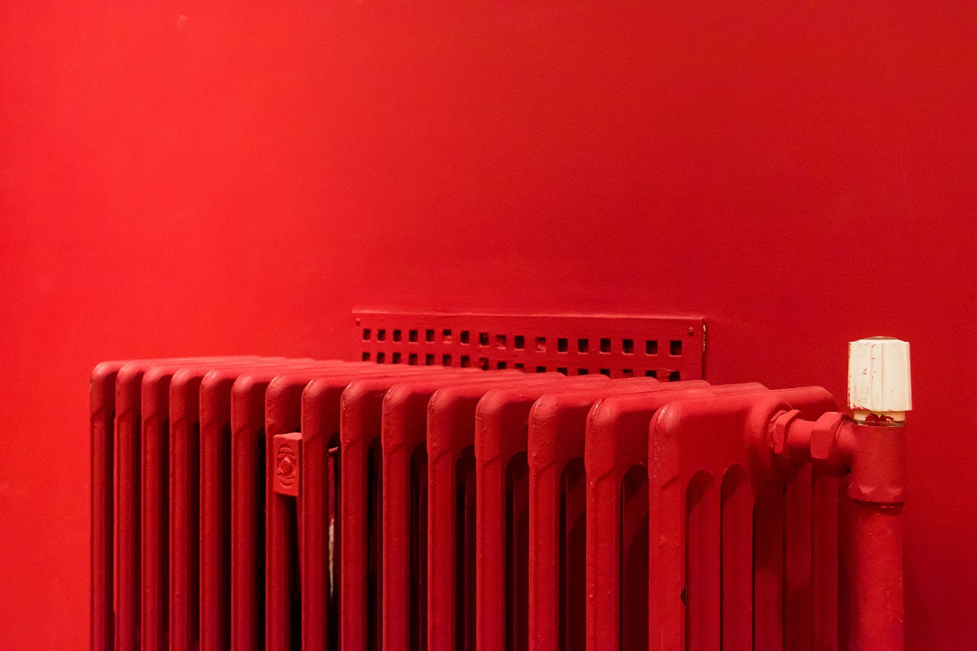 A painted cast iron radiator against a colored wall