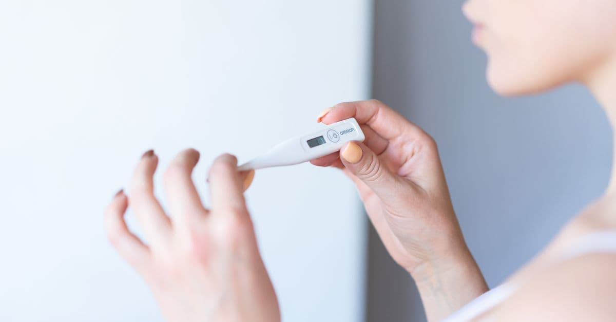 A hand holding a small handheld gauge indoors