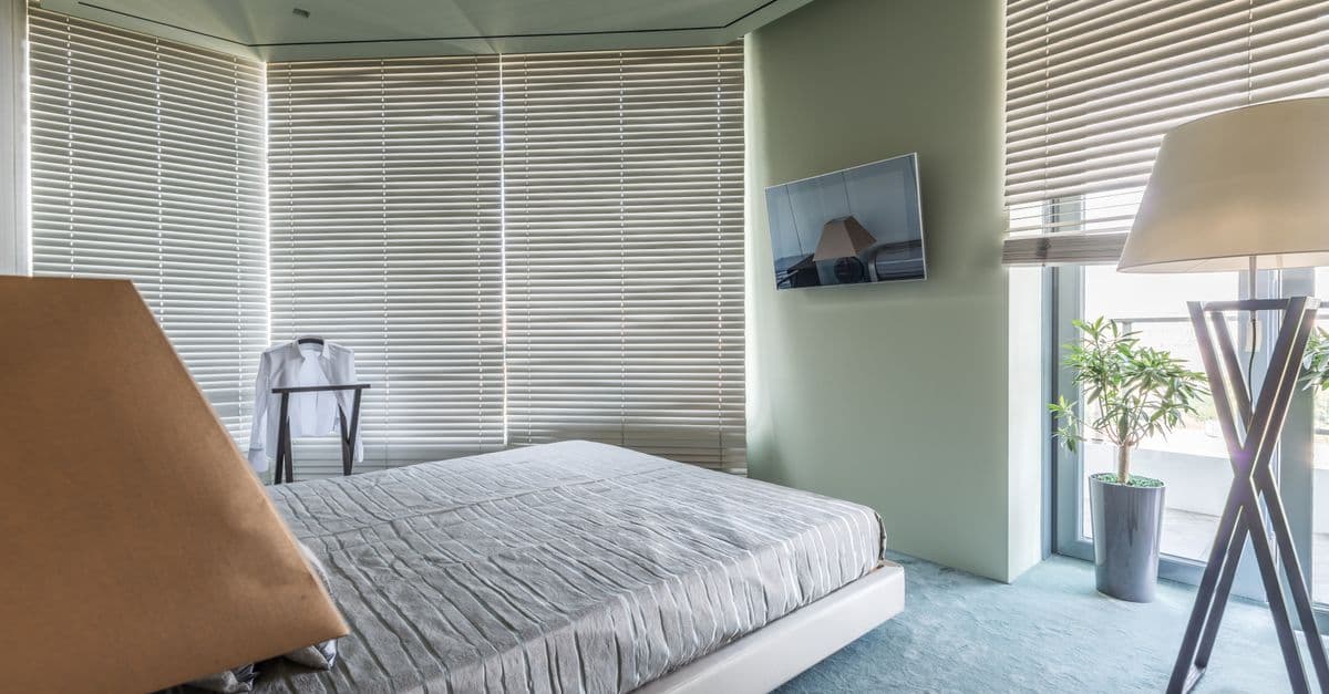 A corner of a modern bedroom with plants beside the bed