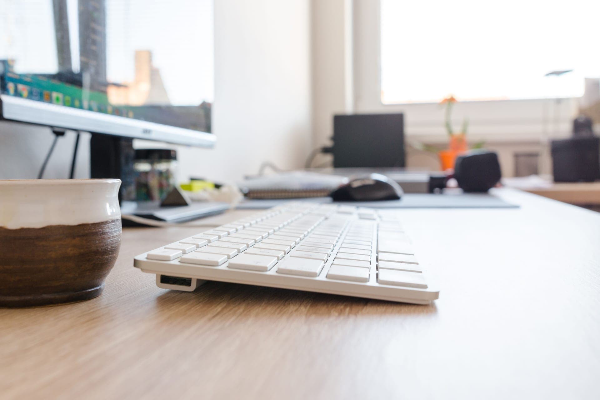 A tidy home office desk with a monitor in daylight
