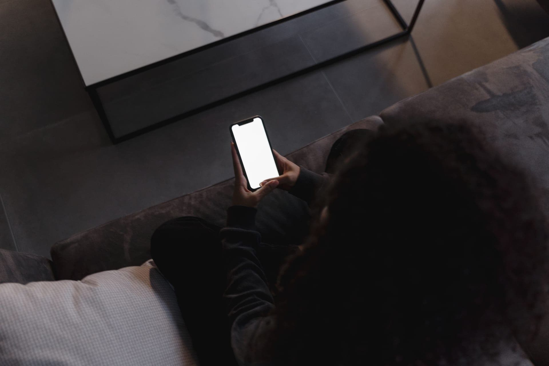 A person holding a smartphone while seated at home
