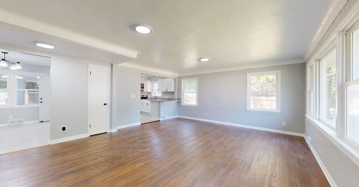 A spacious empty living room with wooden floors in daylight