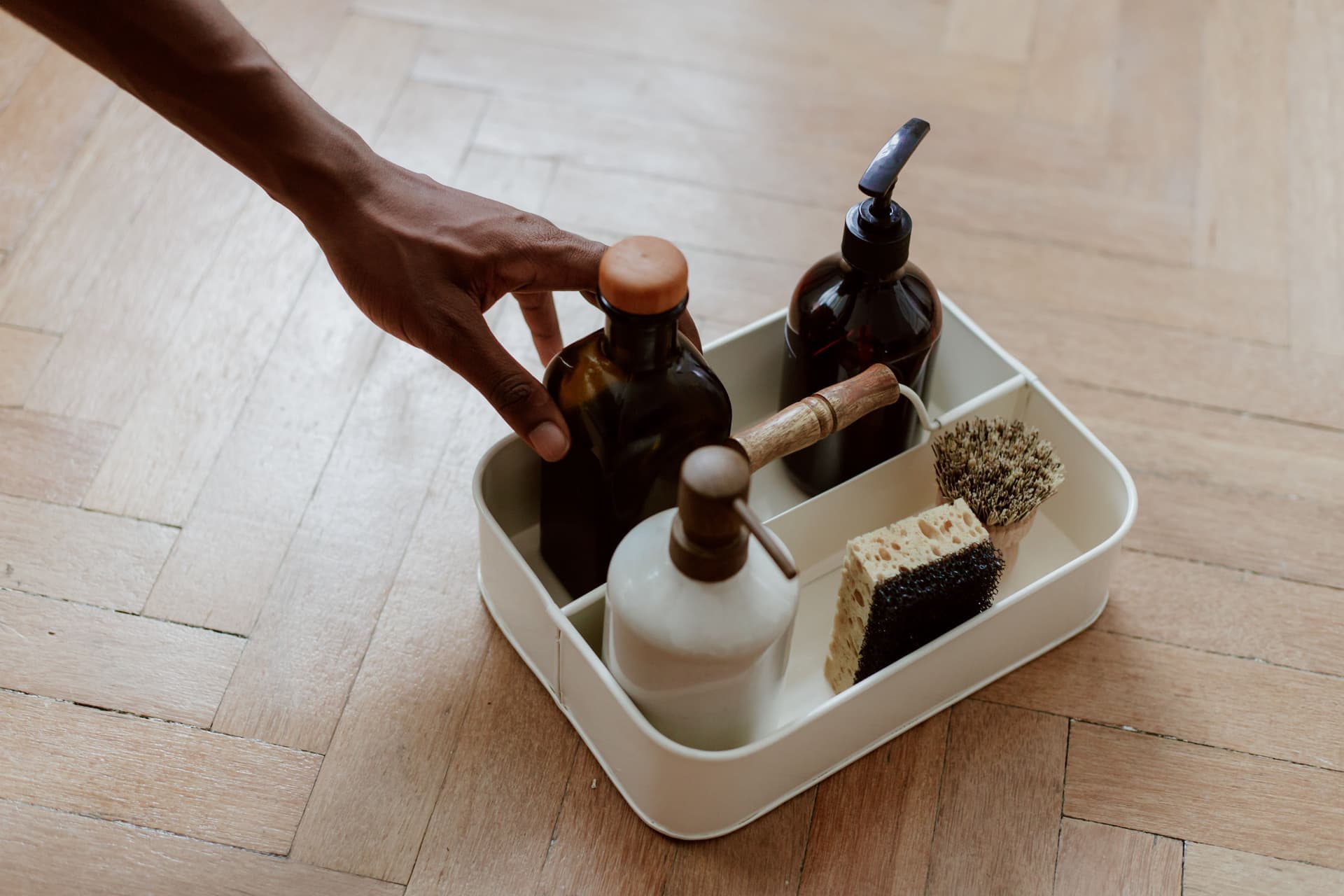 A bottle of white vinegar and a cleaning brush by a sink