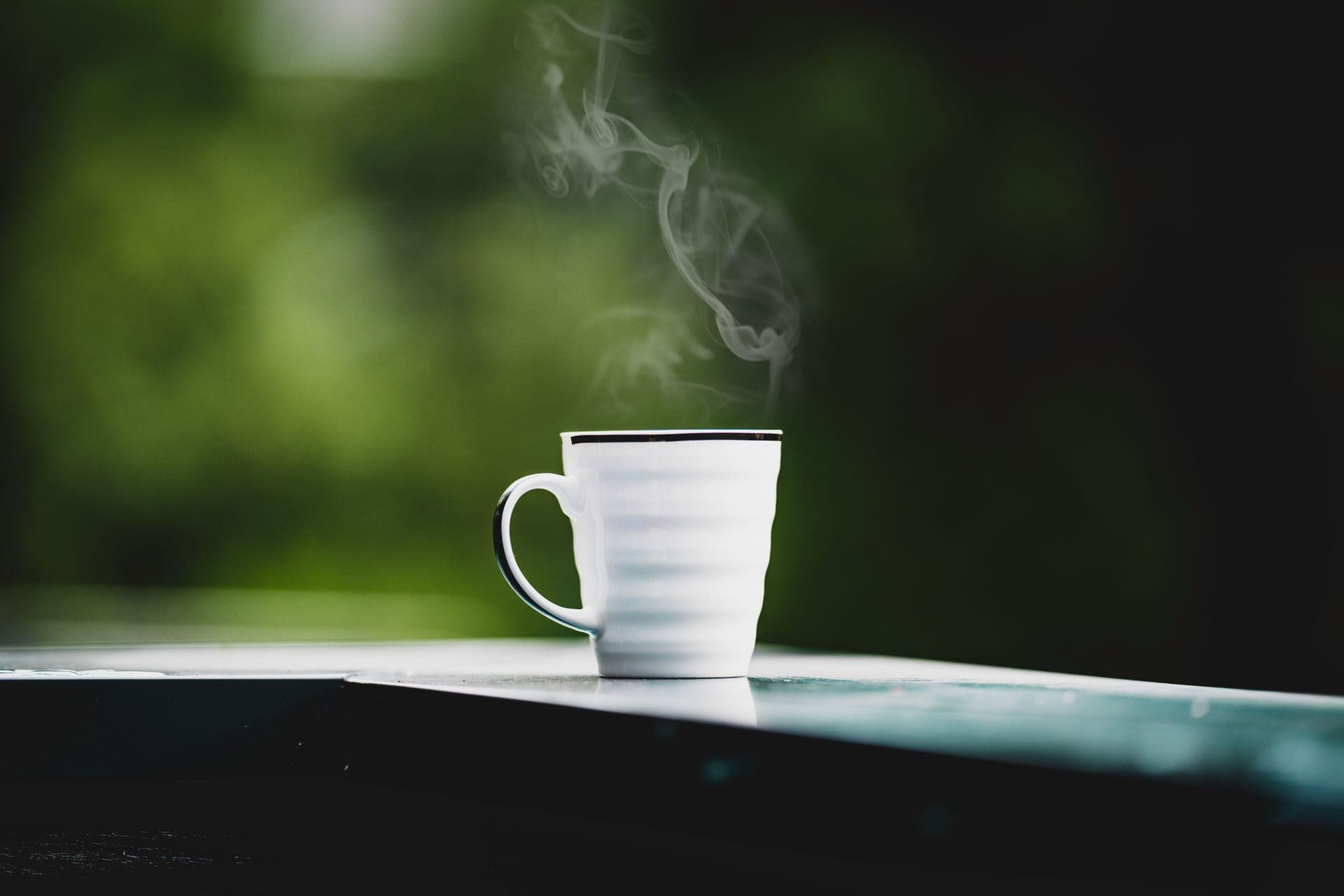 Steam rising from a mug beside a frosted window