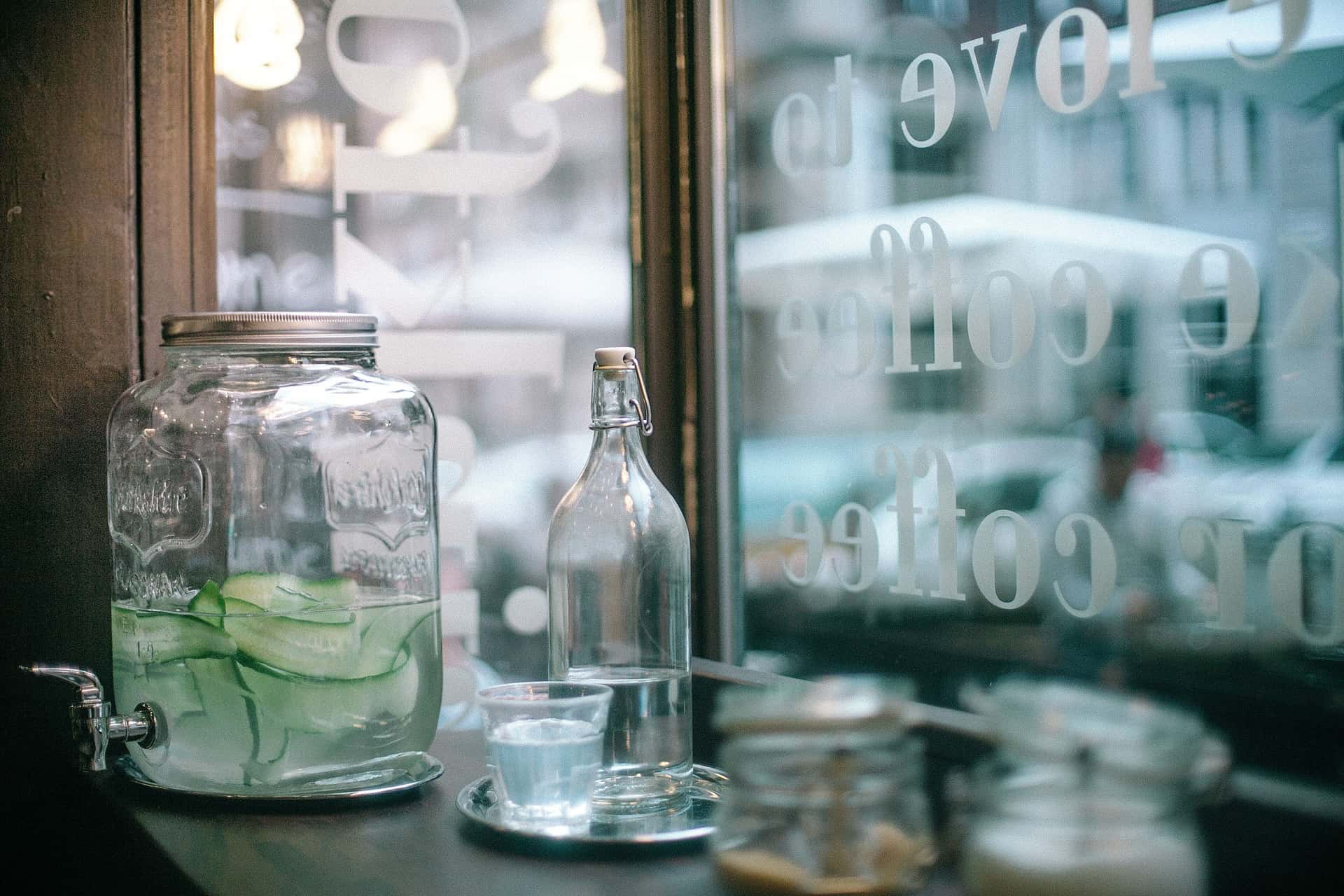 A glass jug and a plastic bottle of water on a counter